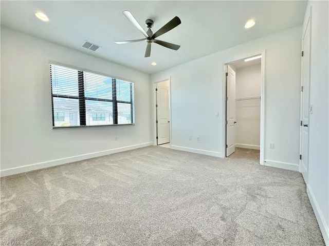 an empty room with windows and ceiling fan