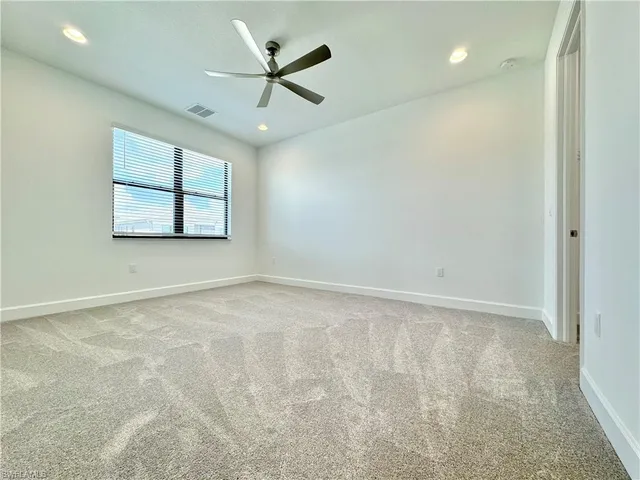 an empty room with windows and ceiling fan