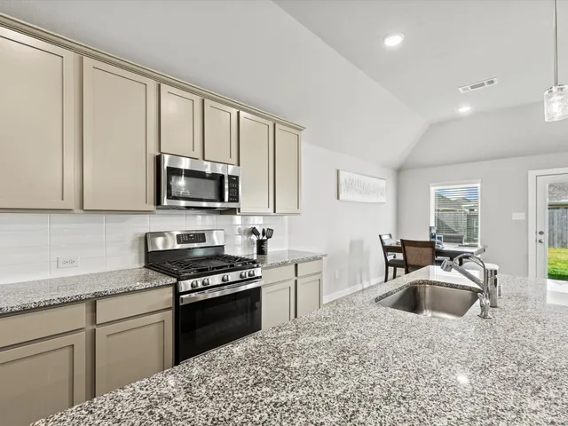 a kitchen with kitchen island granite countertop a sink cabinets and wooden floor