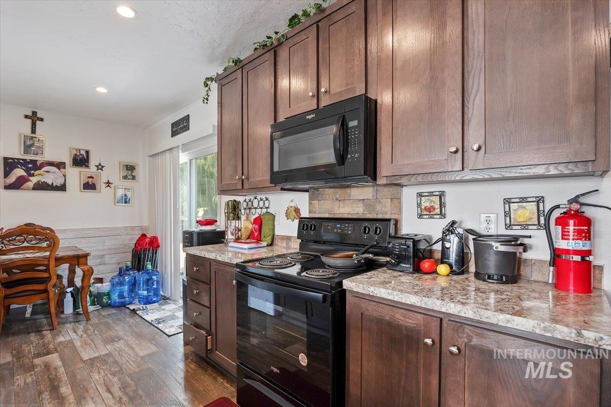121 Sunset Drive North Hagerman, ID 83332 - Photo 10 of 31 Kitchen featuring black appliances, dark brown cabinets, dark wood-style floors, recessed lighting, and a wainscoted wall