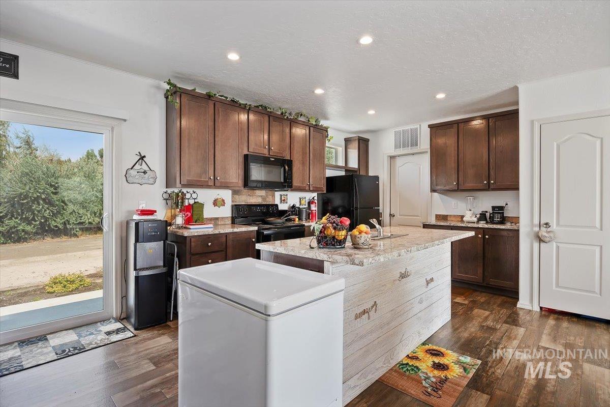 121 Sunset Drive North Hagerman, ID 83332 - Photo 13 of 31 Kitchen with recessed lighting, dark brown cabinetry, dark wood-style flooring, black appliances, and a kitchen island with sink
