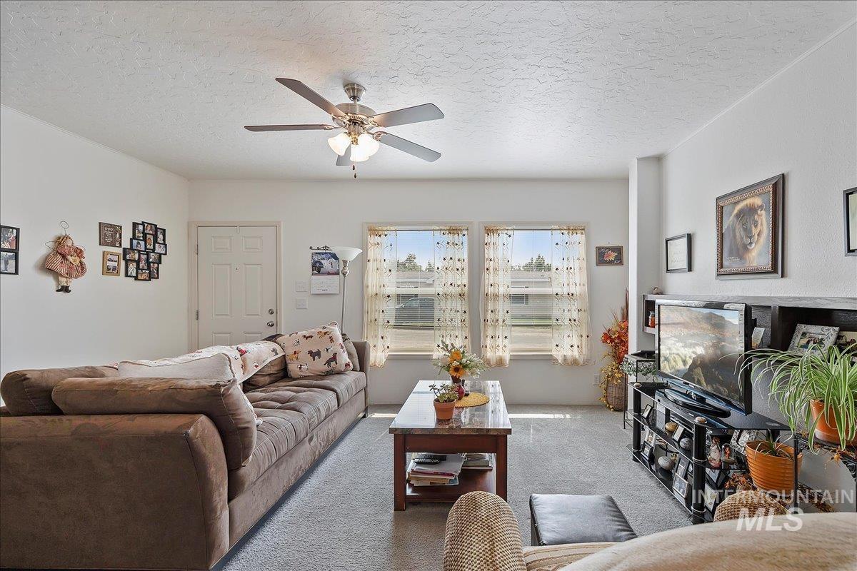 121 Sunset Drive North Hagerman, ID 83332 - Photo 8 of 31 Living room with carpet, a textured ceiling, and a ceiling fan