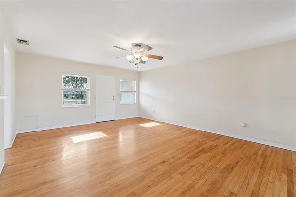 an empty room with wooden floor and windows
