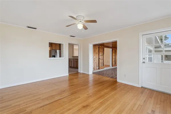 a view of an empty room with wooden floor and a window