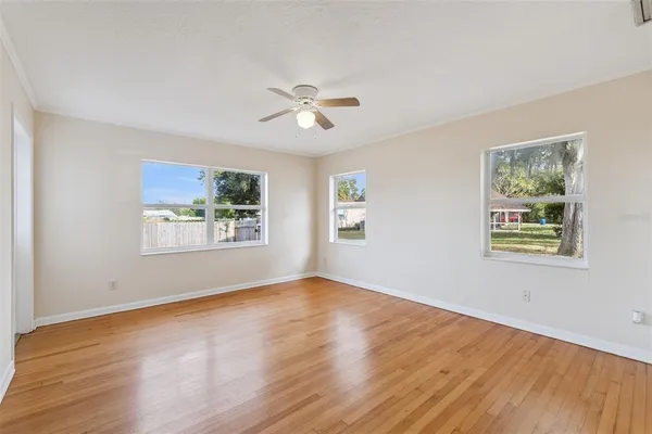 a view of empty room with wooden floor and fan