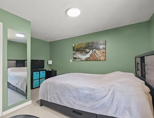 a bedroom with a large bed and a painting on the wall