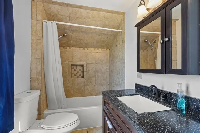 a bathroom with a granite countertop tub sink toilet and mirror