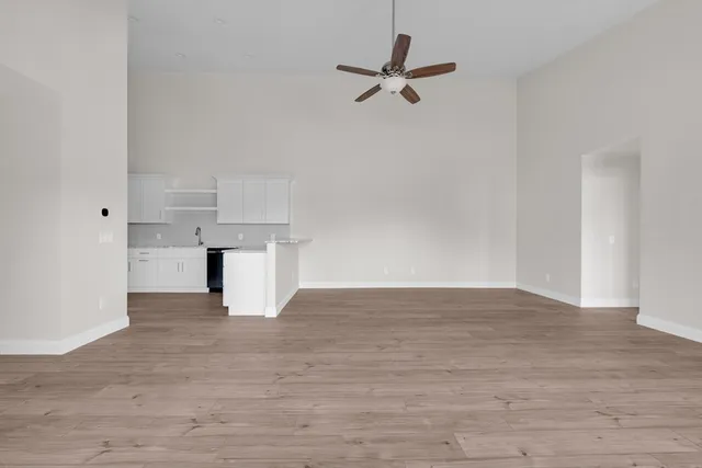 a view of empty room with wooden floor and ceiling fan