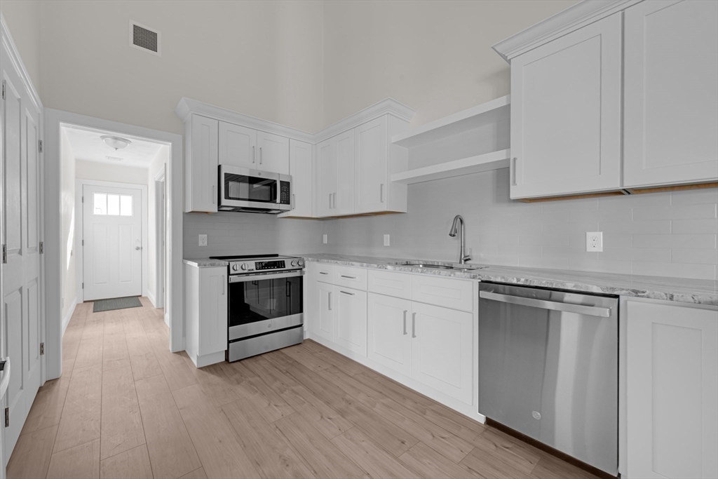7 L Stevens Road, Unit A Charlton, MA 01507 - Photo 7 of 23 a kitchen with granite countertop white cabinets and stainless steel appliances