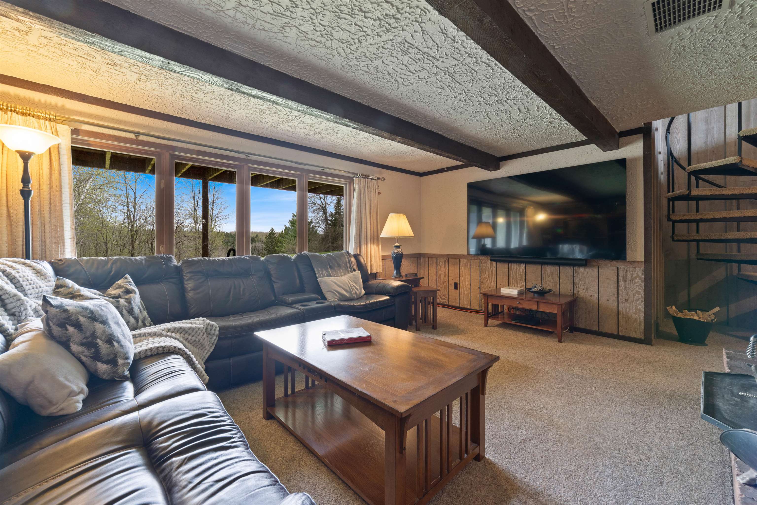 4153 Lindberg Road Superior, WI 54880 - Photo 38 of 52 Carpeted living area with plenty of natural light, wooden walls, beamed ceiling, wainscoting, and a textured ceiling