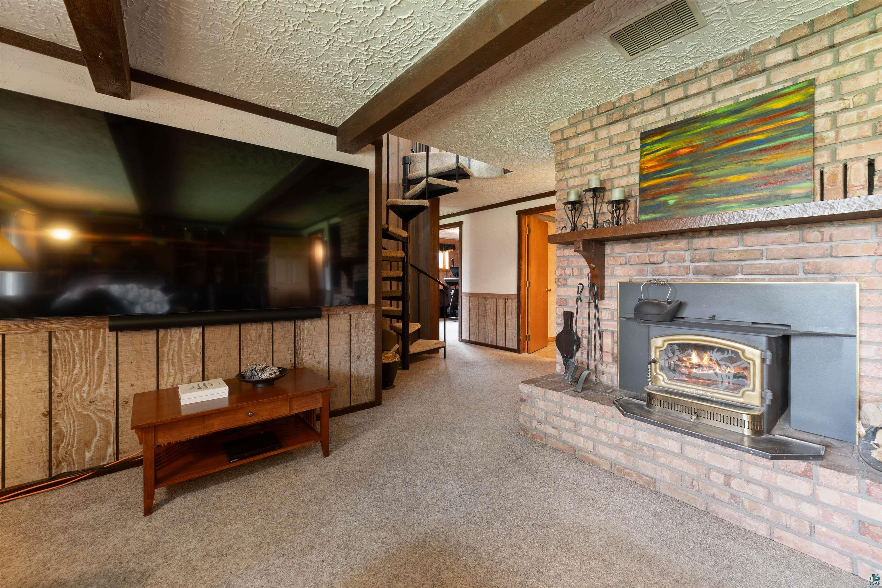 4153 Lindberg Road Superior, WI 54880 - Photo 39 of 52 Carpeted living area with beam ceiling, a textured ceiling, stairway, and a wood stove