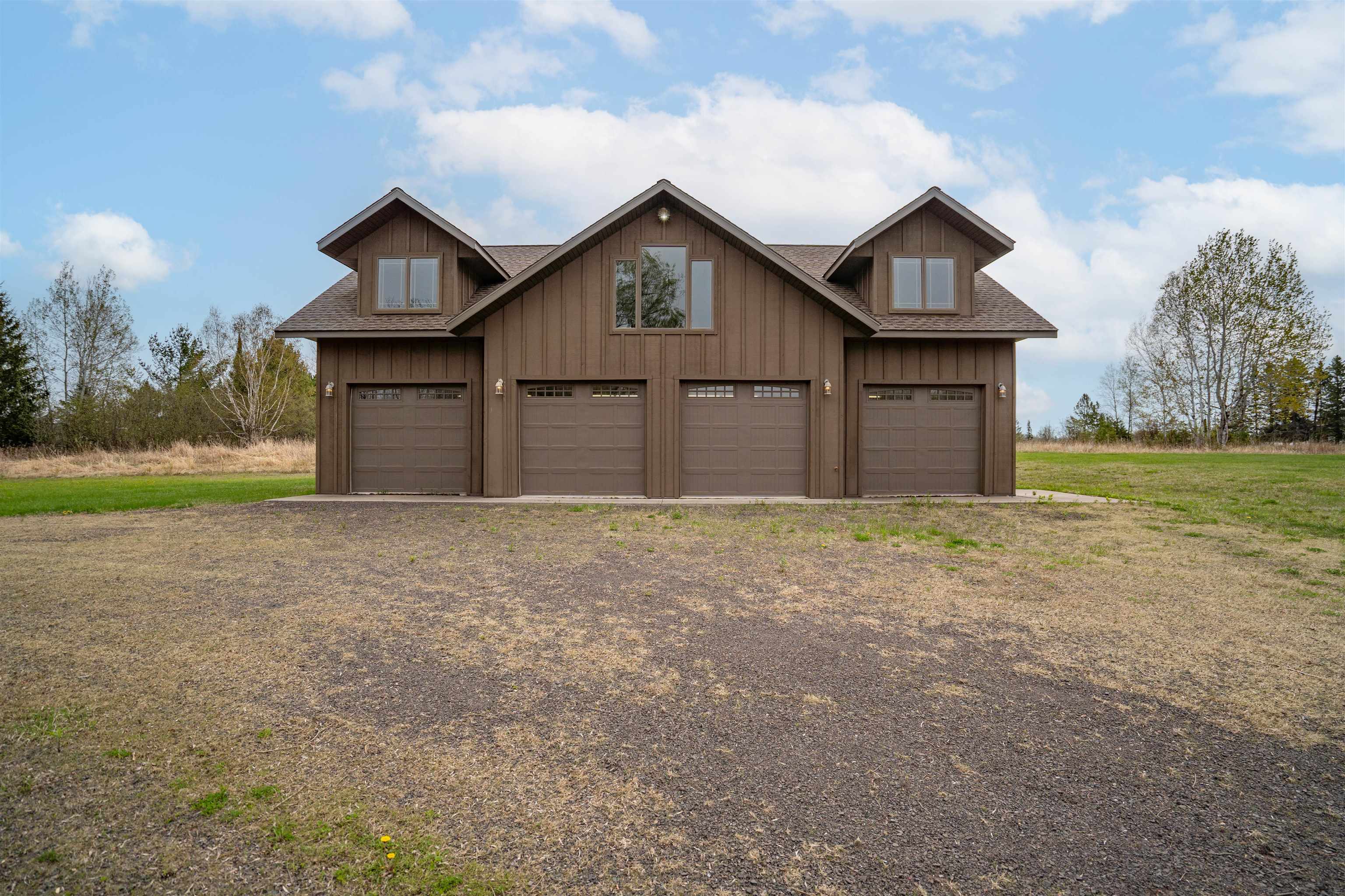 4153 Lindberg Road Superior, WI 54880 - Photo 4 of 52 View of front of property featuring a garage, roof with shingles, board and batten siding, and a front lawn