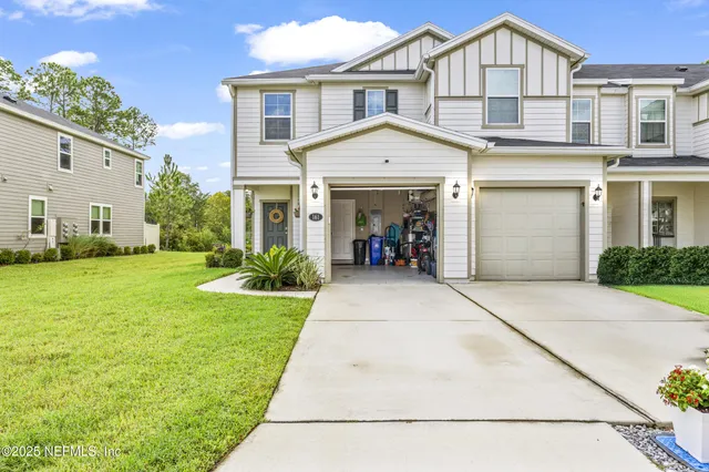a front view of a house with a yard and potted plants