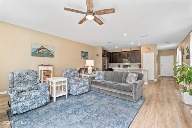a living room with furniture kitchen view and a chandelier