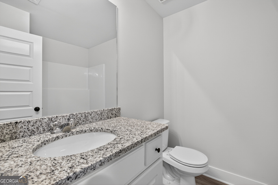 88 Mockingbird Lane, Unit 37 Winder, GA 30680 - Photo 14 of 40 a bathroom with a granite countertop sink a toilet and a mirror