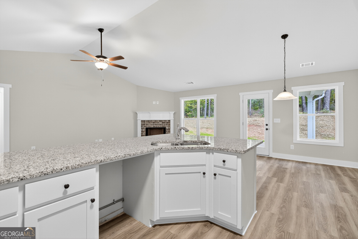 88 Mockingbird Lane, Unit 37 Winder, GA 30680 - Photo 25 of 40 a kitchen with a sink dishwasher and white cabinets with wooden floor