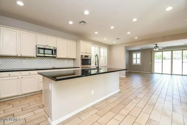 a kitchen with stainless steel appliances kitchen island granite countertop a refrigerator oven a sink dishwasher and white cabinets with wooden floor