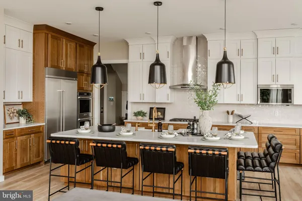 a kitchen with stainless steel appliances granite countertop a refrigerator a sink dishwasher a dining table and chairs with wooden floor