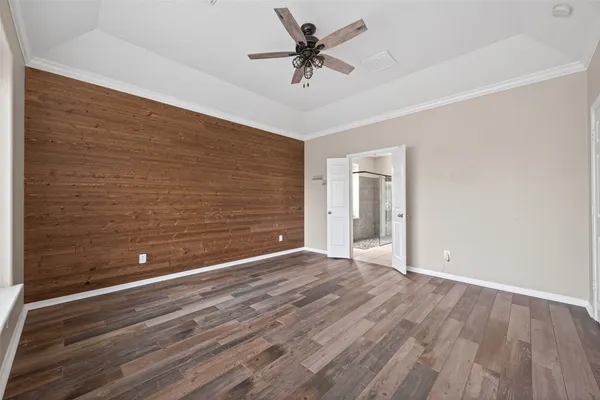 an empty room with wooden floor chandelier fan and windows