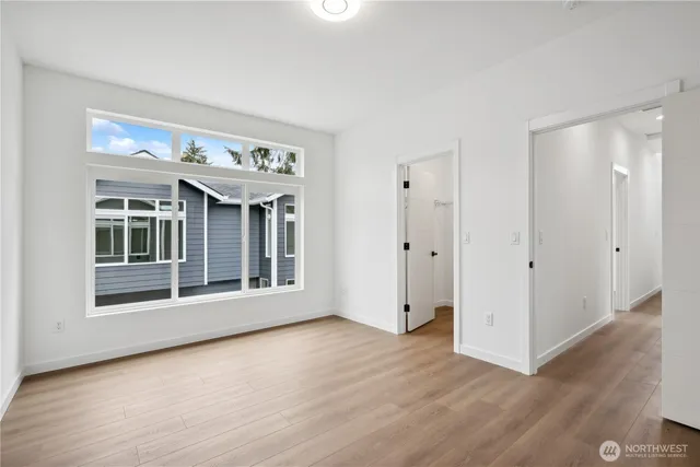 a view of an empty room with wooden floor and windows