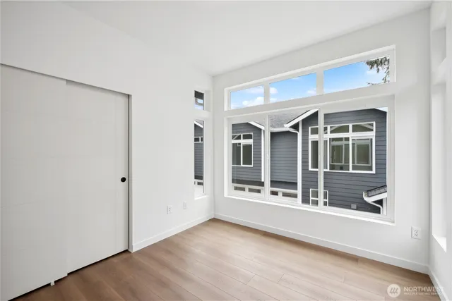 a view of an empty room with wooden floor and windows