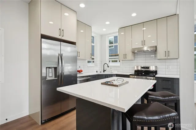 a kitchen with stainless steel appliances granite countertop a stove a refrigerator a sink a dining table and chairs