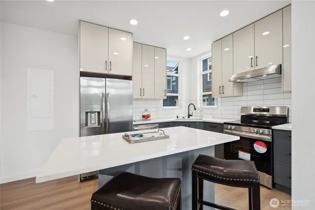 a kitchen with stainless steel appliances a table chairs in it and wooden floor
