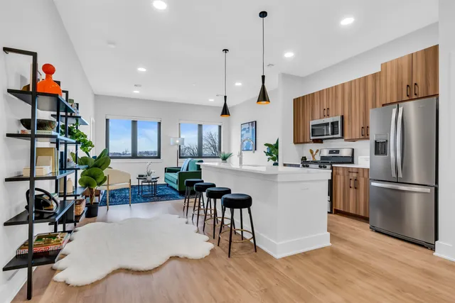 a kitchen with stainless steel appliances granite countertop a refrigerator a stove a microwave oven a dining table and chairs with wooden floor