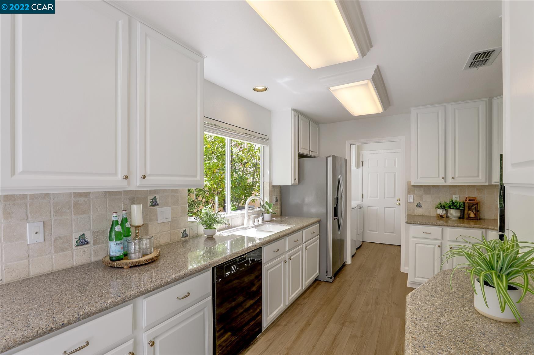 388 Catalan Way San Ramon, CA 94582 - Photo 18 of 52 a kitchen with stainless steel appliances kitchen island granite countertop a refrigerator a sink dishwasher a stove and white cabinets with wooden floor