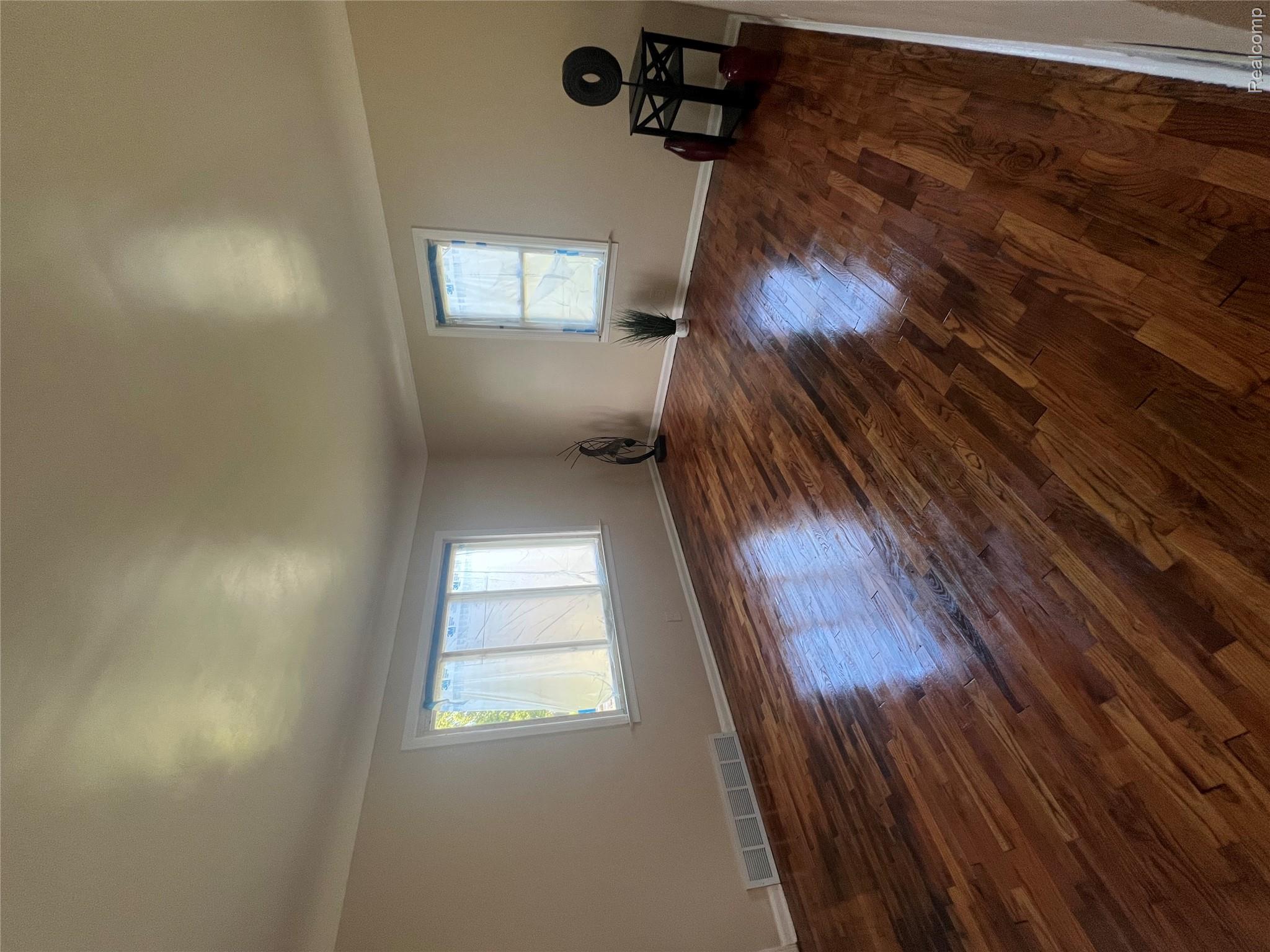 Hardwood flooring with a glossy finish, light-toned wall paint, and white trim molding