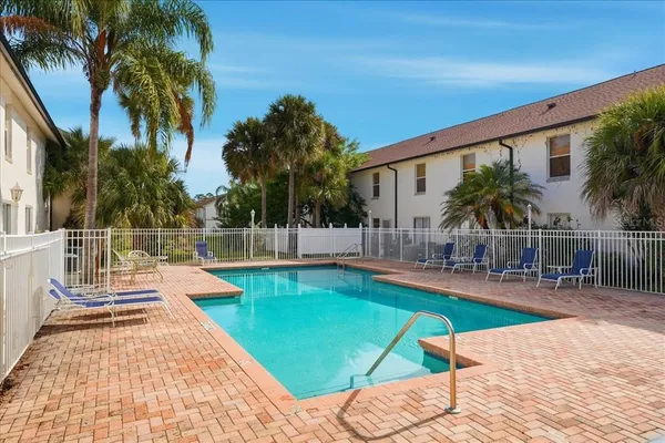 a view of a swimming pool with a lounge chair and palm trees