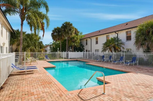 a view of a swimming pool with a lounge chair and palm trees