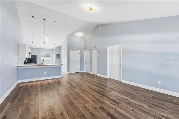 a view of kitchen and empty room with wooden floor