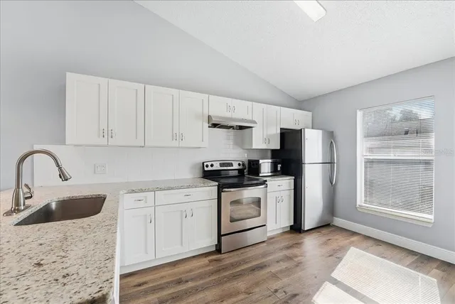 a kitchen with stainless steel appliances granite countertop a refrigerator sink and stove
