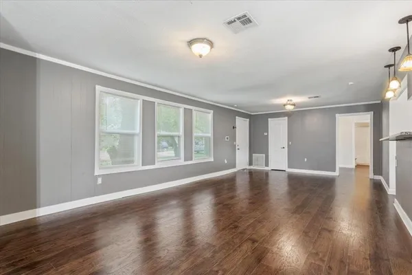 a view of an empty room with wooden floor and a window