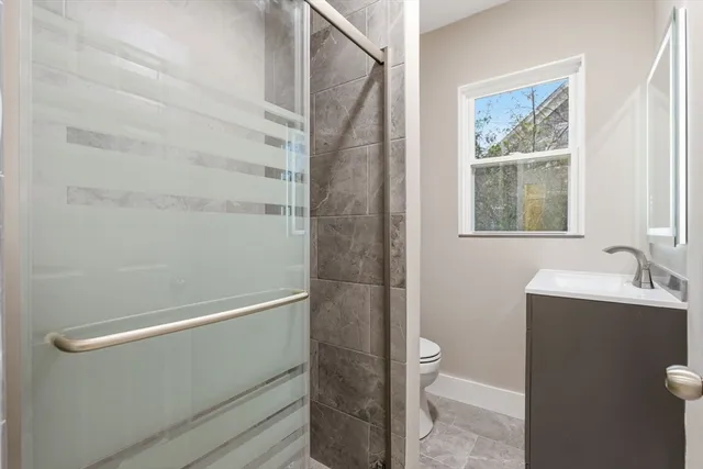a bathroom with a granite countertop sink a toilet and shower