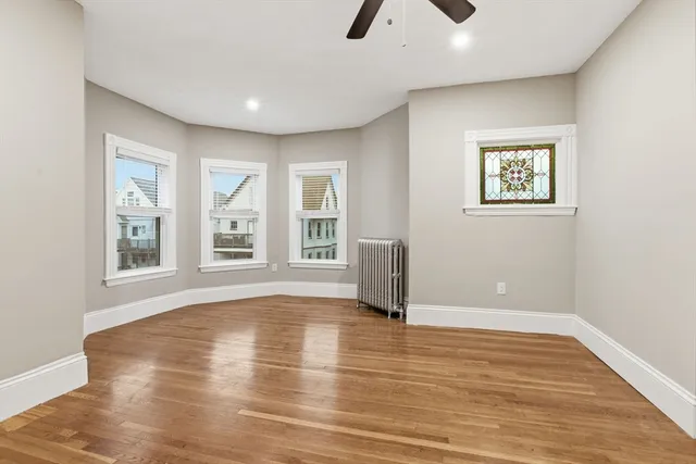a view of an empty room with window and wooden floor