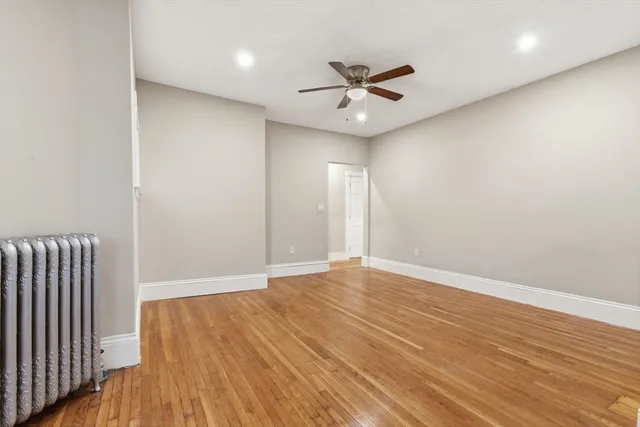an empty room with wooden floor fan and windows