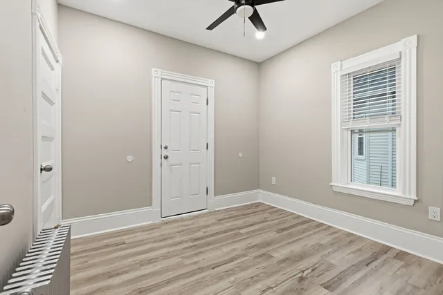 a view of empty room with wooden floor and fan