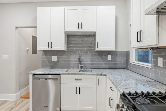 a kitchen with granite countertop a sink stove and cabinets