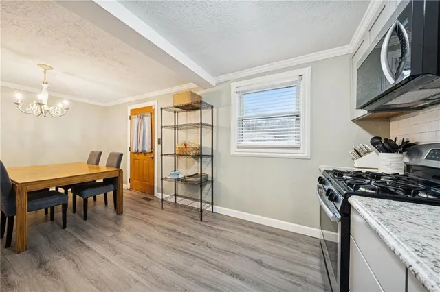 a kitchen with stainless steel appliances granite countertop a stove top oven a sink dishwasher and a dining table with wooden floor