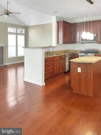 a kitchen with stainless steel appliances granite countertop a stove a sink dishwasher and a refrigerator with wooden floor