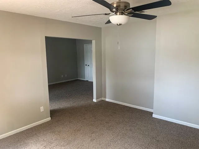 an empty room with a fan & a window