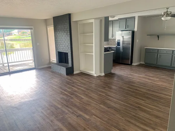 a view of a kitchen with wooden floor electronic appliances and windows