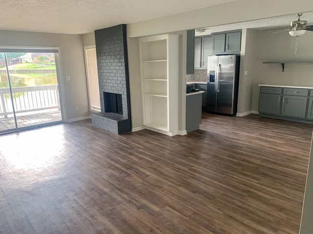 a view of a kitchen with wooden floor electronic appliances and windows