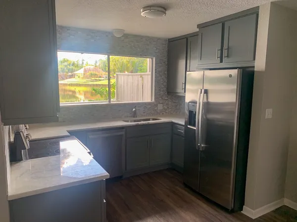 a kitchen with stainless steel appliances granite countertop a sink a refrigerator and a window