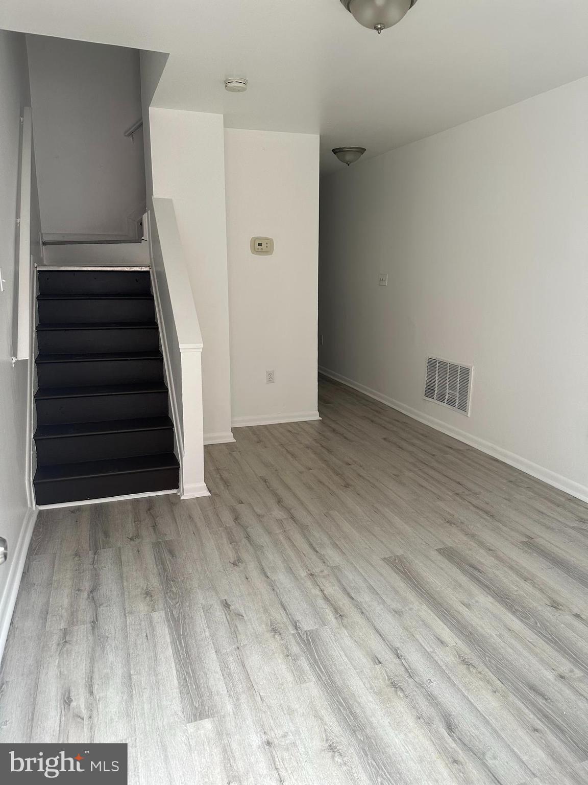 1707 North Dallas Street Baltimore, MD 21213 - Photo 3 of 12 a view of an empty room with wooden floor and stairs