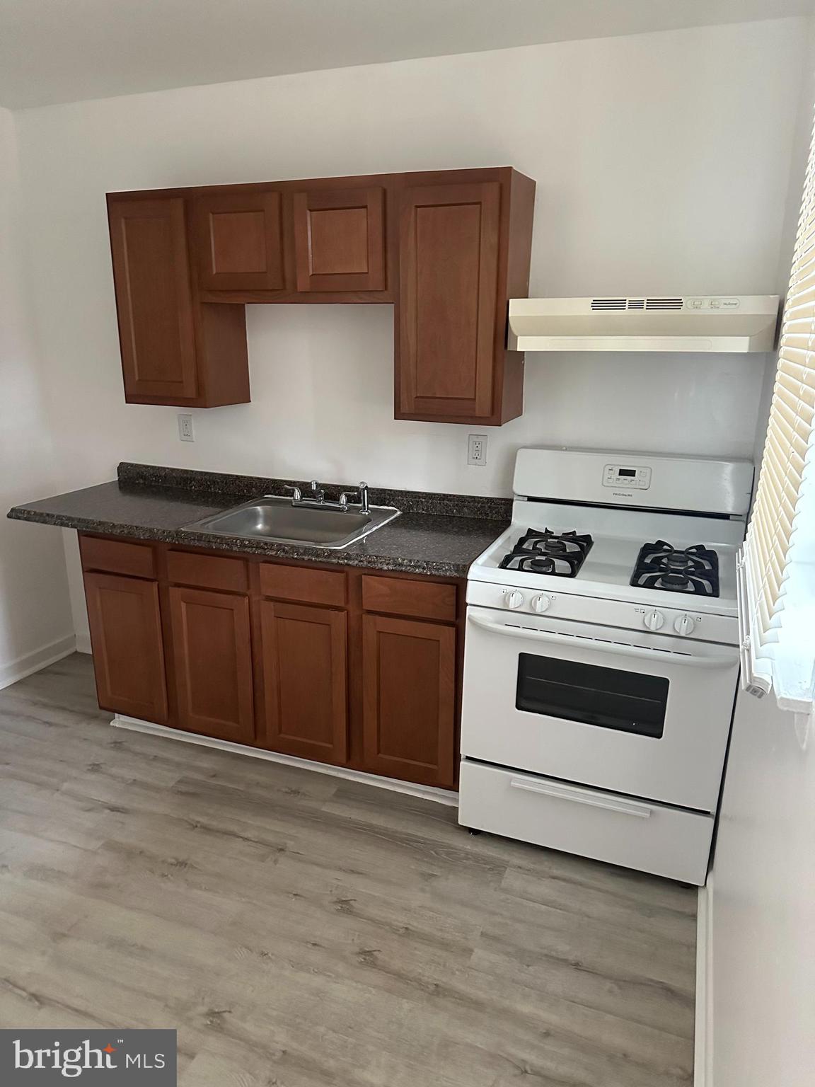 1707 North Dallas Street Baltimore, MD 21213 - Photo 5 of 12 a kitchen with granite countertop wooden cabinets and white appliances