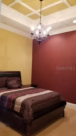 a bedroom with a bed chandelier and a window