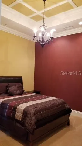 a bedroom with a bed chandelier and a window